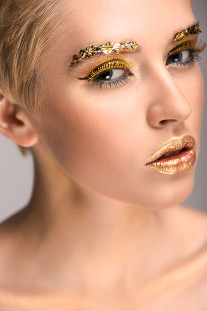 attractive caucasian woman with golden glitter on face looking at camera - Photo, Image