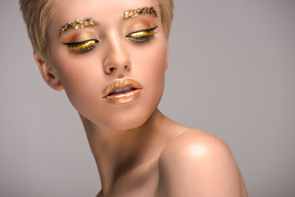 attractive woman with golden shiny makeup looking down isolated on grey - Foto, Bild