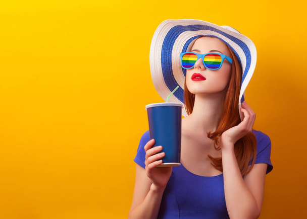 Redhead girl with drink and rainbow sunglasses - Фото, изображение