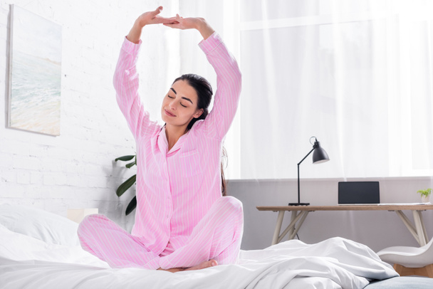 mujer en pijama estirándose en la cama por la mañana en casa
 - Foto, Imagen