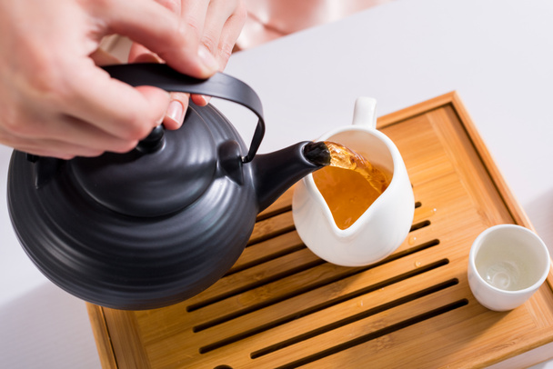 partial view of woman pouring tea into jug while having tea ceremony at home - Photo, Image