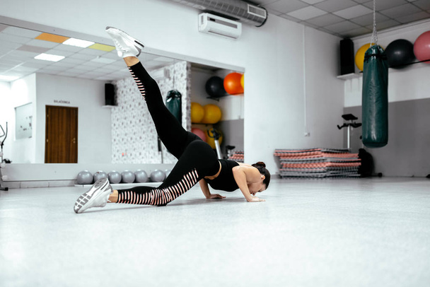Side view of young woman doing press-ups core exercise at the gym. - Foto, afbeelding