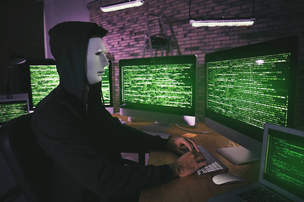 Masked hacker in room with computers - Foto, Bild