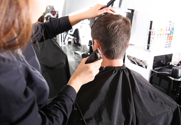 Professional stylist cutting client's hair in salon - Foto, afbeelding