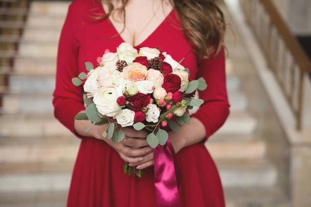 Bride in a red dress. Bridesmaid in a red dress. Wedding bouquet with a red ribbon - 写真・画像