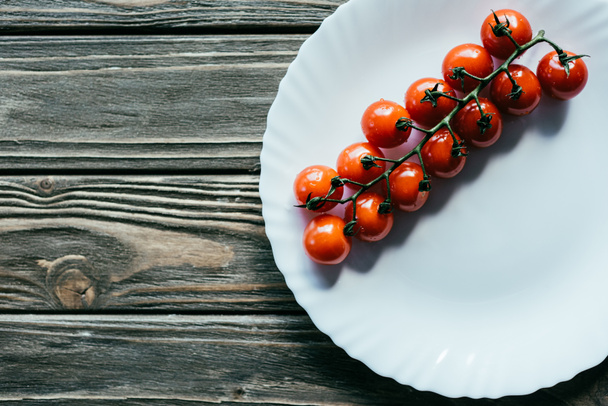 Cherry tomatoes on white plate on wooden table - Photo, Image