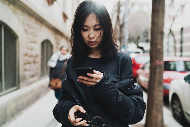 Young asian woman using smartphone while walking street - Fotoğraf, Görsel
