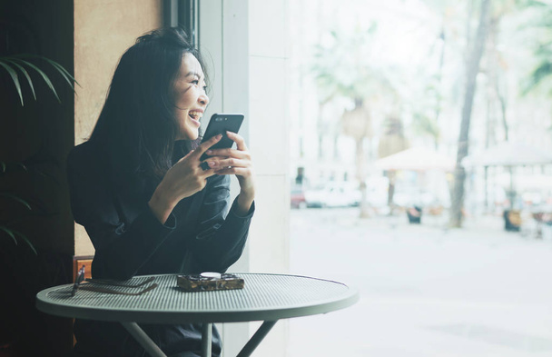 Успешная молодая женщина сидит в кафе и использует смартфон
 - Фото, изображение