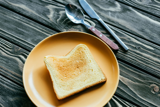 Pane tostato su piatto con posate su tavolo di legno
 - Foto, immagini