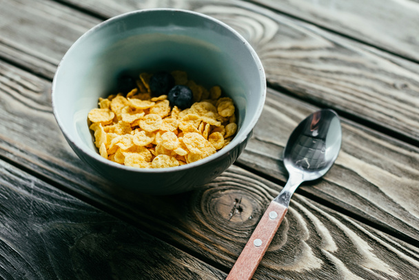 Corn flakes with berries on wooden table - 写真・画像