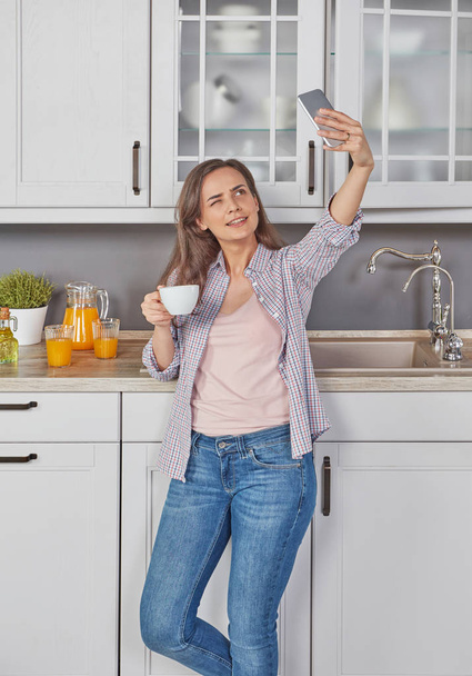 Cheerful woman enjoying a coffee and making a selfie - Foto, afbeelding