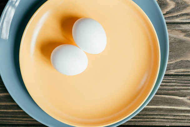 White chicken eggs on plate on wooden table - 写真・画像