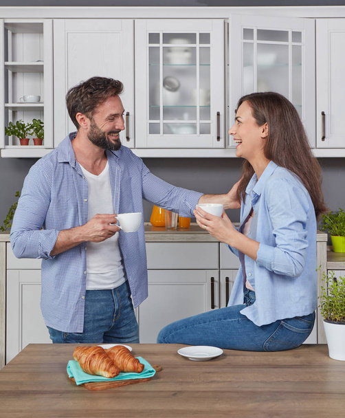 Young couple in love in the kitchen enjoying a coffee - Фото, изображение