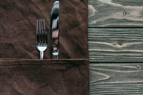 Set de cubiertos con servilleta marrón sobre mesa de madera
 - Foto, Imagen