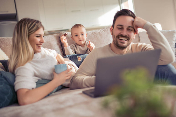 Ευτυχισμένη οικογένεια απολαμβάνει στο σπίτι και βλέποντας κινούμενα σχέδια σε φορητό υπολογιστή - Φωτογραφία, εικόνα
