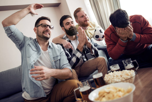 Baráti néz foci játék a televízióban, ételeket eszik és iszik sört - Fotó, kép