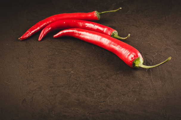 Three red Chile pepper on a dark background/Three red hot Chile pepper on a dark background. Copy space - Foto, Imagen
