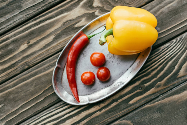 Papryka i Pomidory czereśniowe w srebrnej tacy na drewnianym stole - Zdjęcie, obraz