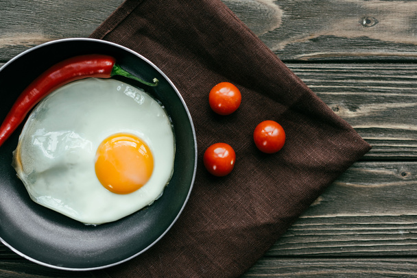 Breakfast with fried egg and tomatoes on textile napkin - Photo, Image