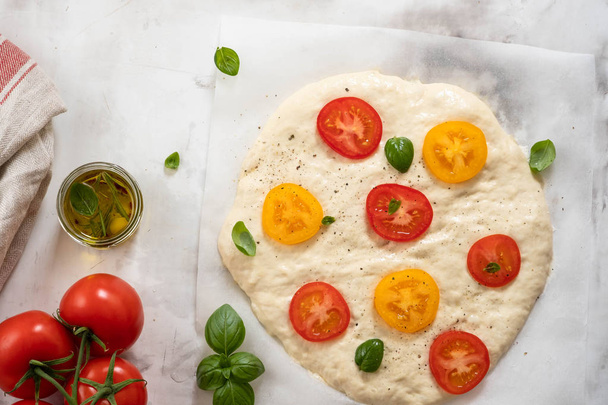Dough for pizza or focaccia with ingredients, tomatoes, basil, olive oil. Top view. - Foto, immagini