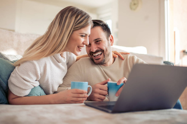 joven pareja sentado usando portátil y viendo vídeo en casa
 - Foto, Imagen