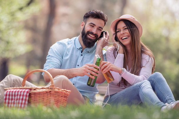 Feliz pareja joven haciendo un picnic en el parque en un día soleado
 - Foto, imagen