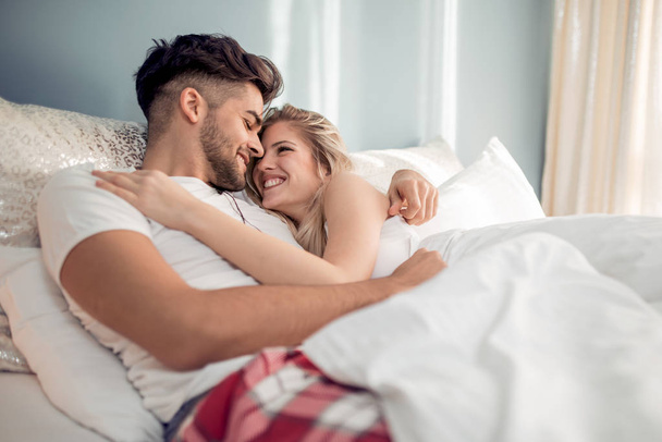 幸せな愛情のあるカップルが自宅のベッドで一緒に横になっています。 - 写真・画像