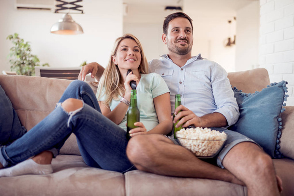 Casal assistindo tv e comer pipocas em casa
 - Foto, Imagem