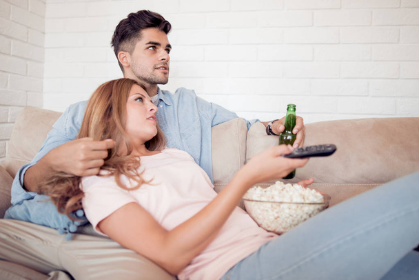 Couple watching tv and eating popcorn at home - Foto, imagen
