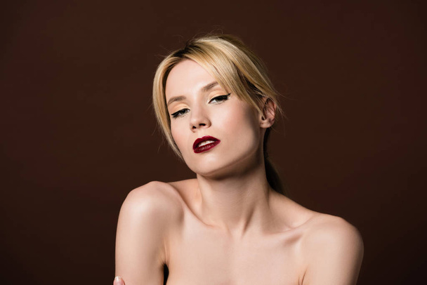 portrait of beautiful naked young blonde woman looking at camera isolated on brown - Photo, Image