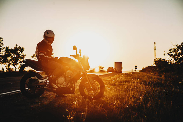 Toller kaukasischer Abenteurer, der im Urlaub mit seinem Fahrrad vor dem Sonnenuntergang für den Fotografen posiert. - Foto, Bild