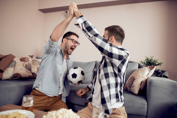 Feliz macho amigos viendo fútbol en la televisión en casa
 - Foto, Imagen