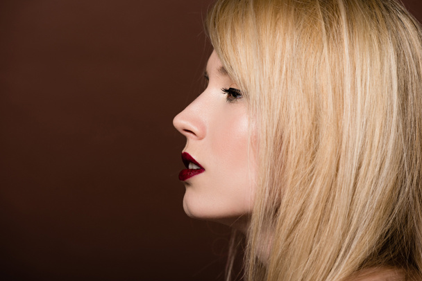 вид збоку красива молода блондинка дивиться ізольовано на коричневий
  - Фото, зображення