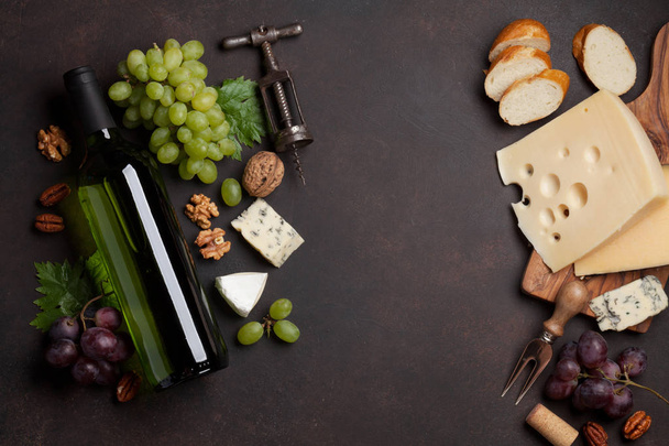 Wein, Trauben, Brot, Nüsse und Käse auf dunklem Steingrund. Ansicht von oben mit Platz für Ihren Text - Foto, Bild