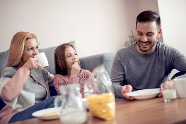 happy mother, father and daughter having breakfast at home - Foto, immagini
