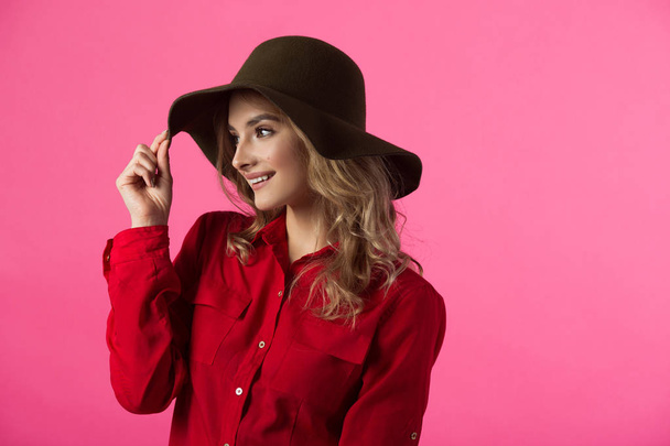 beautiful joyful young girl in a red shirt and hat on a pink background - Photo, Image