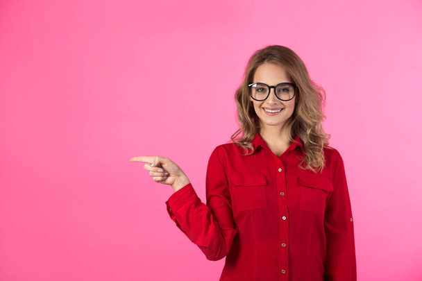 beautiful joyful young girl in a red shirt on a pink background with a gesture of hands - Fotografie, Obrázek