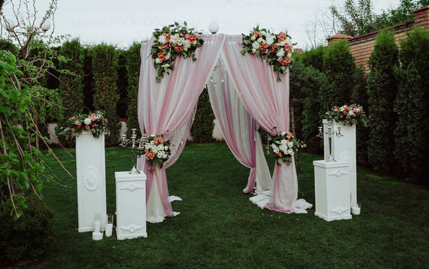 pink wedding arch, decorated with flowers stands in the garden - Φωτογραφία, εικόνα