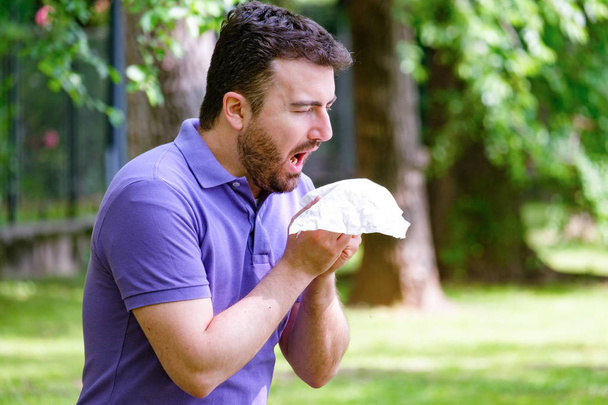 Hombre con alergia o enfermo con fiebre del heno estornudos y limpieza nasal
 - Foto, imagen