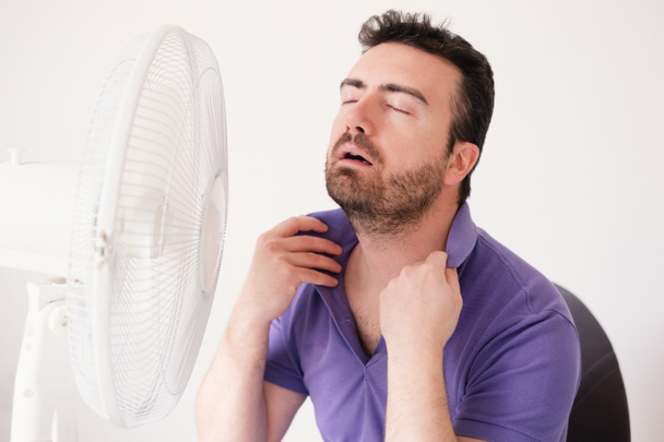 Homme rafraîchissant devant ventilateur électrique de l'air
 - Photo, image