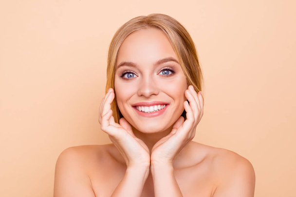 Nude, charming, pretty, cute, toothy cheerful girl with beaming smile perfect face skin after detox, vitamins, collagen holding hands on cheek, isolated on beige background, wellness wellbeing concept - Fotó, kép