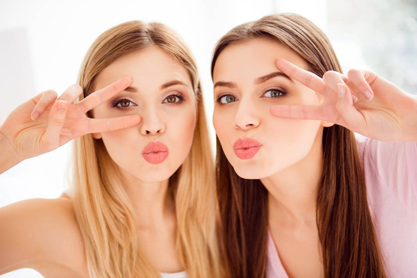 Attractive, cheerful, stylish, pretty, lovely, brunette, blonde, charming, cute, confident, successful, sexy girlfriends showing v-signs near eyes sending, blowing kiss with pout lips, looking at camera - Foto, Imagen
