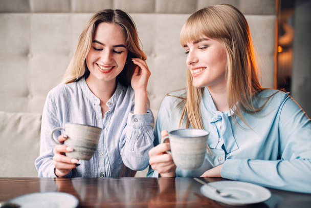 two happy female friends drinking coffee in cafe - Photo, Image