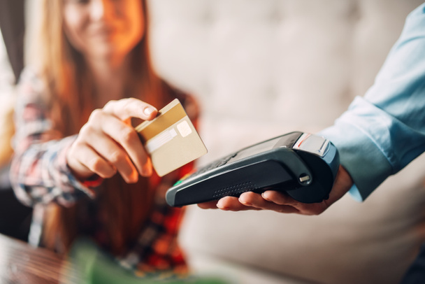 молода жінка платить кредитною карткою в кафе, рука офіціанта з терміналом, сучасна технологія оплати
 - Фото, зображення