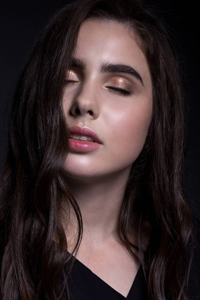 Klassieke portret van een tienermeisje in een zwart shirt op een zwarte achtergrond, close-up. avond make-up. - Foto, afbeelding