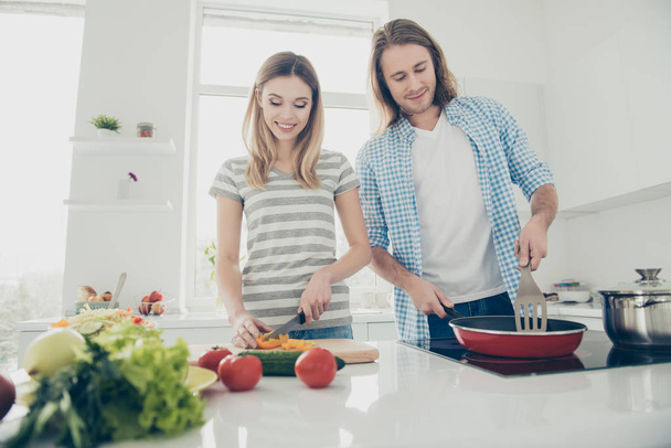Bottom view portrait of stylish professional partners preparing lunch together enjoying rest relax keeping healthy lifestyle standing in modern white kitchen. Weight loss concept - Valokuva, kuva
