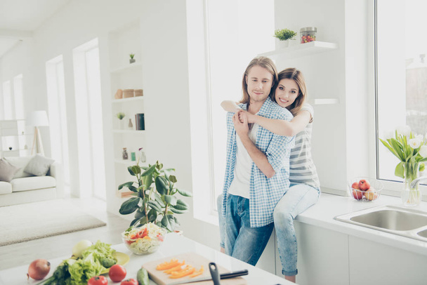 Portrait of trendy attractive couple enjoying time together while preparing dinner in modern white kitchen. True feelings big love concept - Photo, image