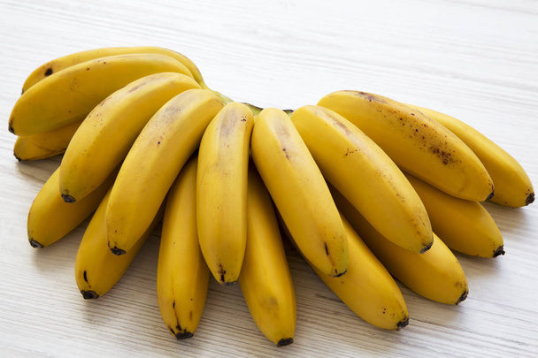Bunch of baby banana on a white wooden background. Closeup. - Photo, Image