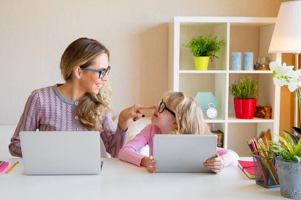 Мать и дочь сидят за столом и используют компьютеры вместе
 - Фото, изображение