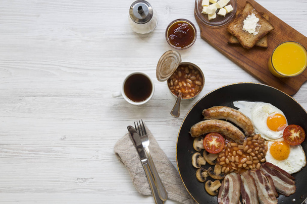 Kompletní anglická snídaně v misce s sázená vejce, slanina, fazole, klobásky a toasty na bílém pozadí dřevěná, pohled shora. Kopírovat prostoru. Byt leží. Z výše uvedeného.  - Fotografie, Obrázek